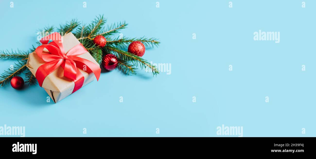 Festive box with a red bow on a blue background with Christmas toys balls branch of fluffy spruce sparkles and confetti . New Year Christmas concept Stock Photo