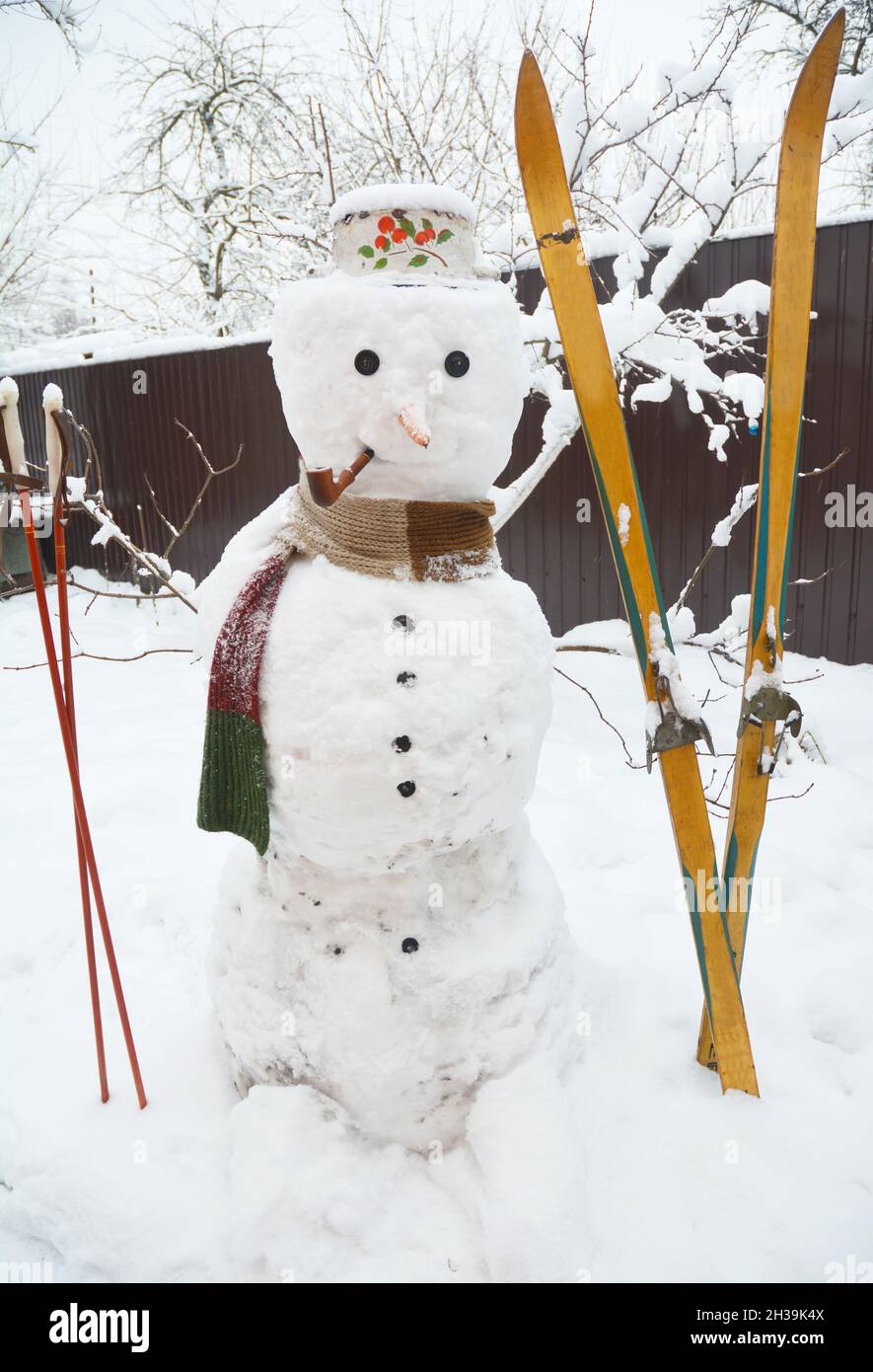 snow tobacco Winter Snowman with scarf and skiing. Christmas Snowman in hat with tobacco  pipe Stock Photo