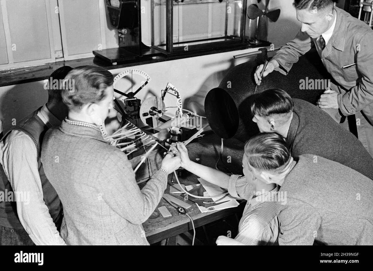 Flugschüler schauen sich anhand eines Modells die Steuerung eines Flugzeuges an, Deutschland 1930er Jahre. Pilot trainees studying the steering of a plane by observing a model, Germany 1930s. Stock Photo