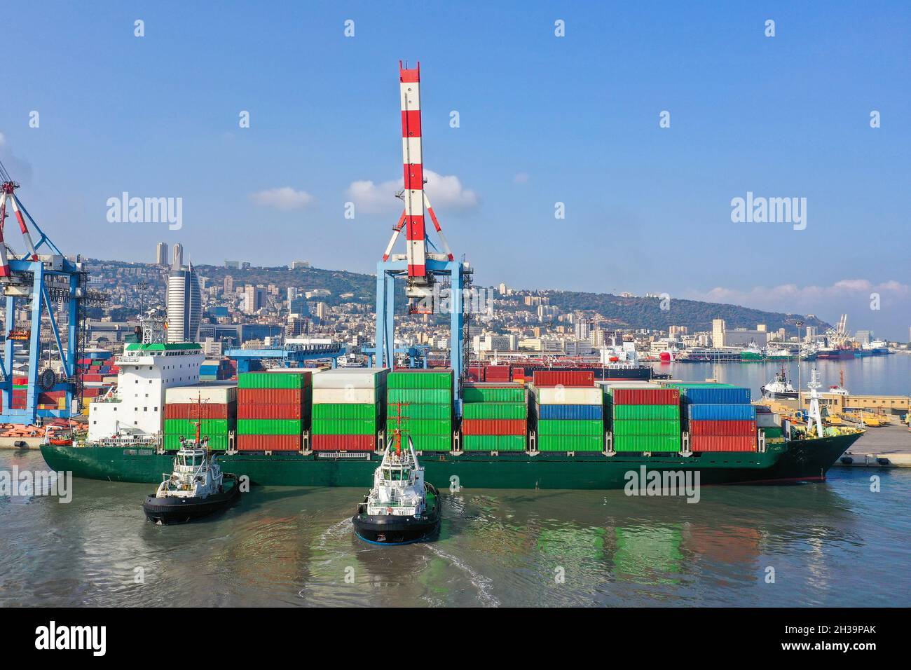 Tug boats directing a Container ship into a port dock. Stock Photo