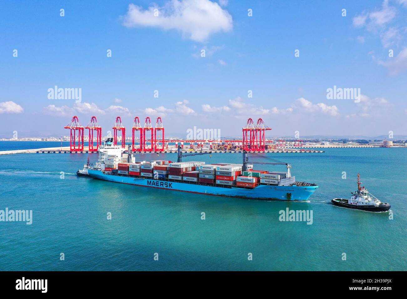 Tug boats directing a Maersk Container ship into a port dock. Stock Photo