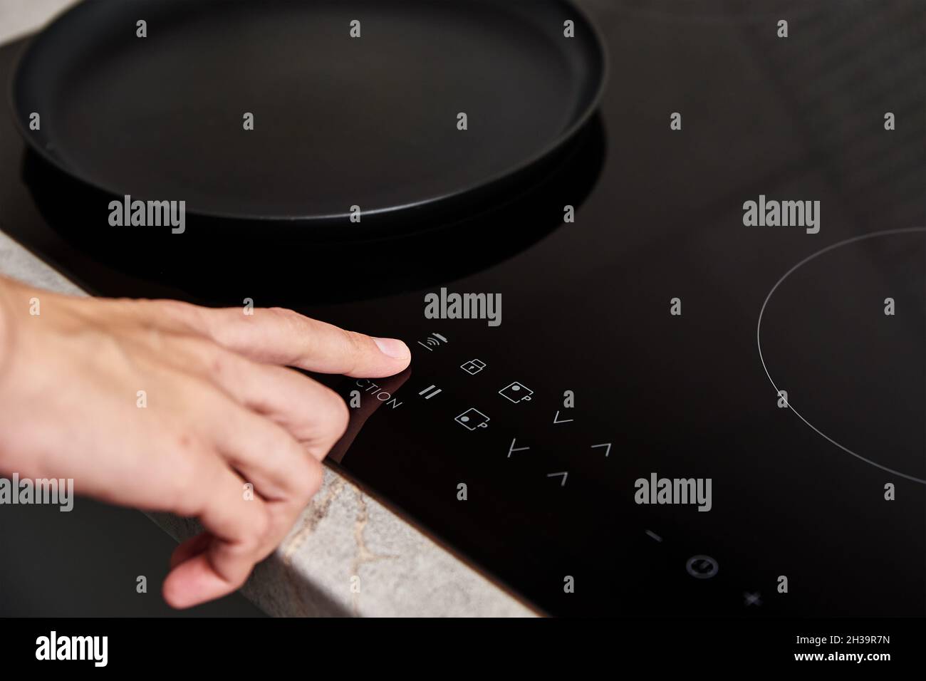 Modern kitchen appliance. Woman hand turn on induction stove to cook