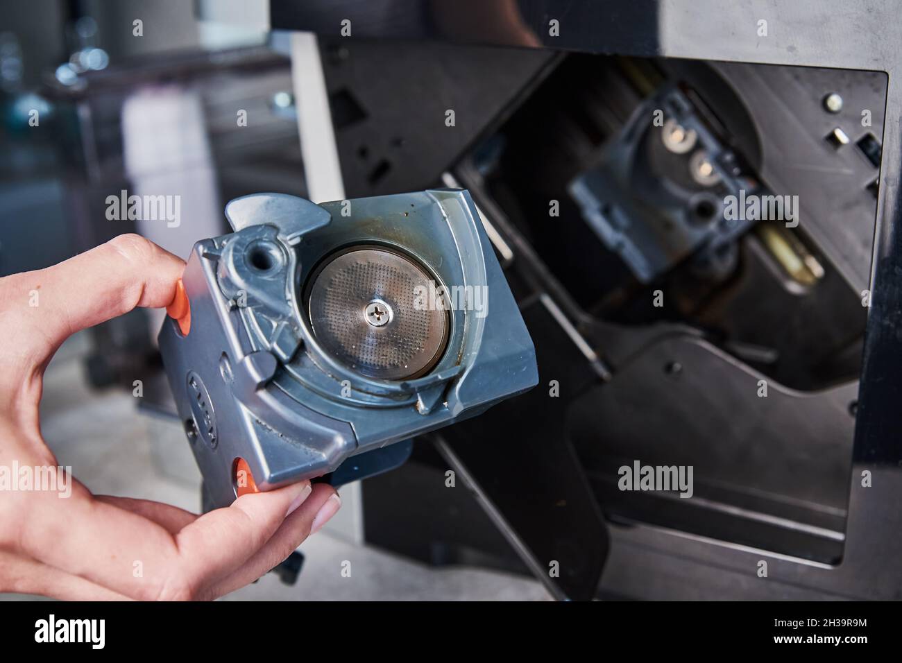 Automatic coffee machine cleaning. Woman inserts mechanism inside