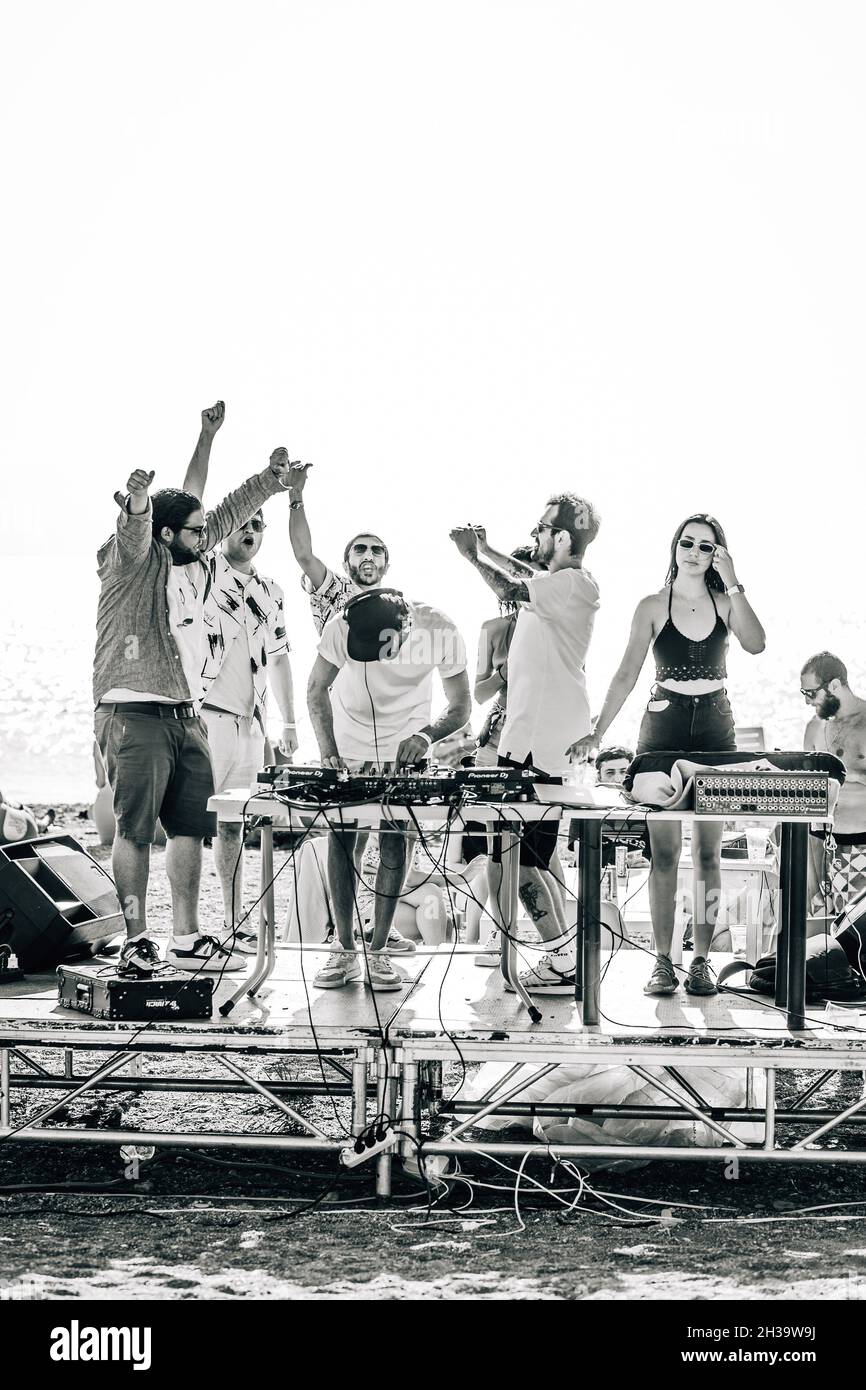 SEVAN, ARMENIA - Sep 03, 2021: A monochrome shot of a group of friends partying on a small concert stage at the beach in Lake Sevan Stock Photo