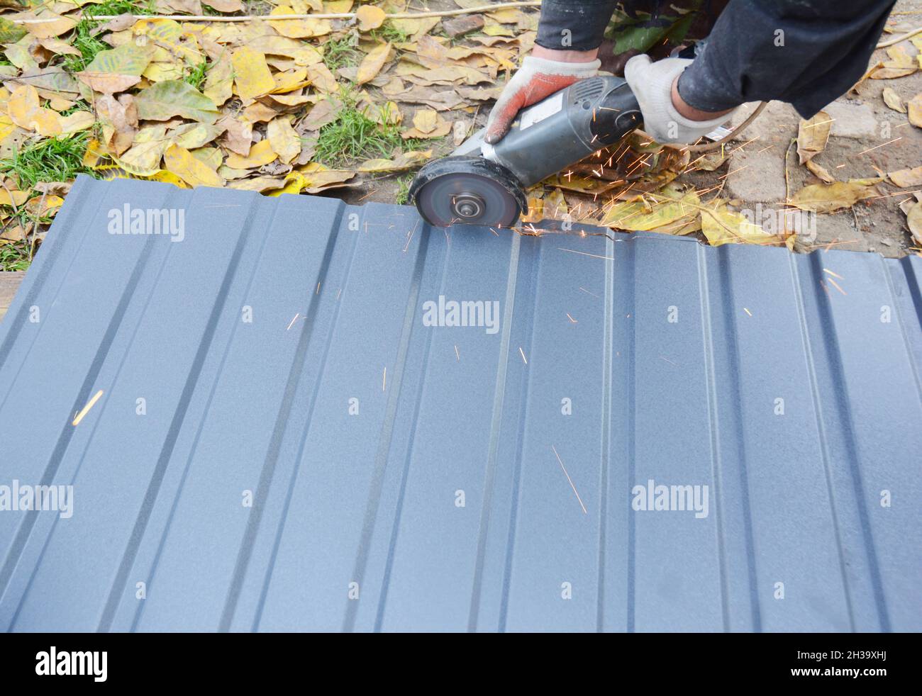 Roofer cutting metal roof sheets, metal tile for house roofing construction. Cut metal tile roof