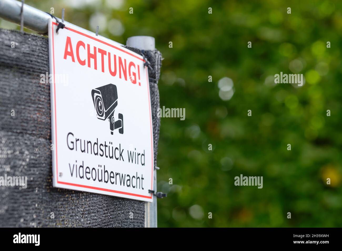 Nuremberg, Germany - October 07, 2021: Close-up of sign at fence of a construction site telling pedestrians Achtung! Grundstück wird videoüberwacht ( Stock Photo