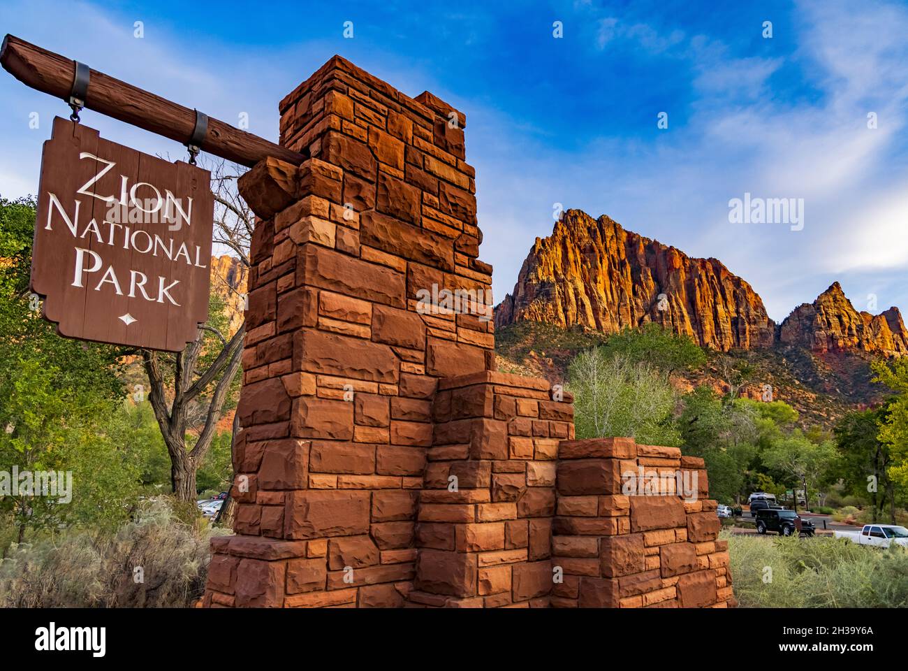 This is a view of the sign at the walk-in entrance to Zion National Park, Springdale, Washington County, Utah, USA.  The Watchman is in the distance. Stock Photo