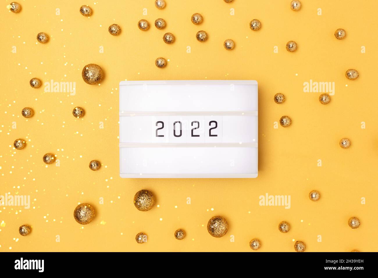 Lightbox with 2022 numbers on a golden background with round confetti. Stock Photo