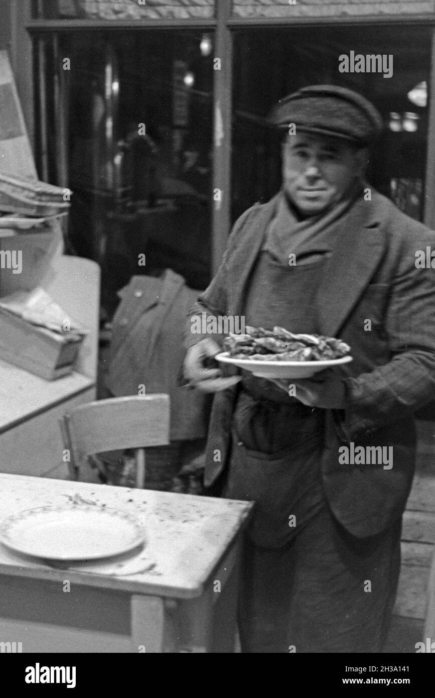 Ein Mann hat sich ein paar belegte Brote als Mahlzeit geholt in Paris, Frankreich 1930er Jahre. A man with a plate of sandwiches at Paris, France 1930s. Stock Photo