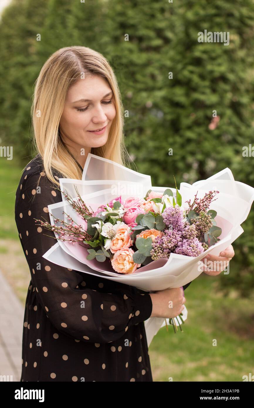 Girl holding flowers in her hands. A girl looking bouquet. Bouquet of roses hands of girl. Flower bouquet. Bunch of flowers. Flower arrangement of vivid color Stock Photo