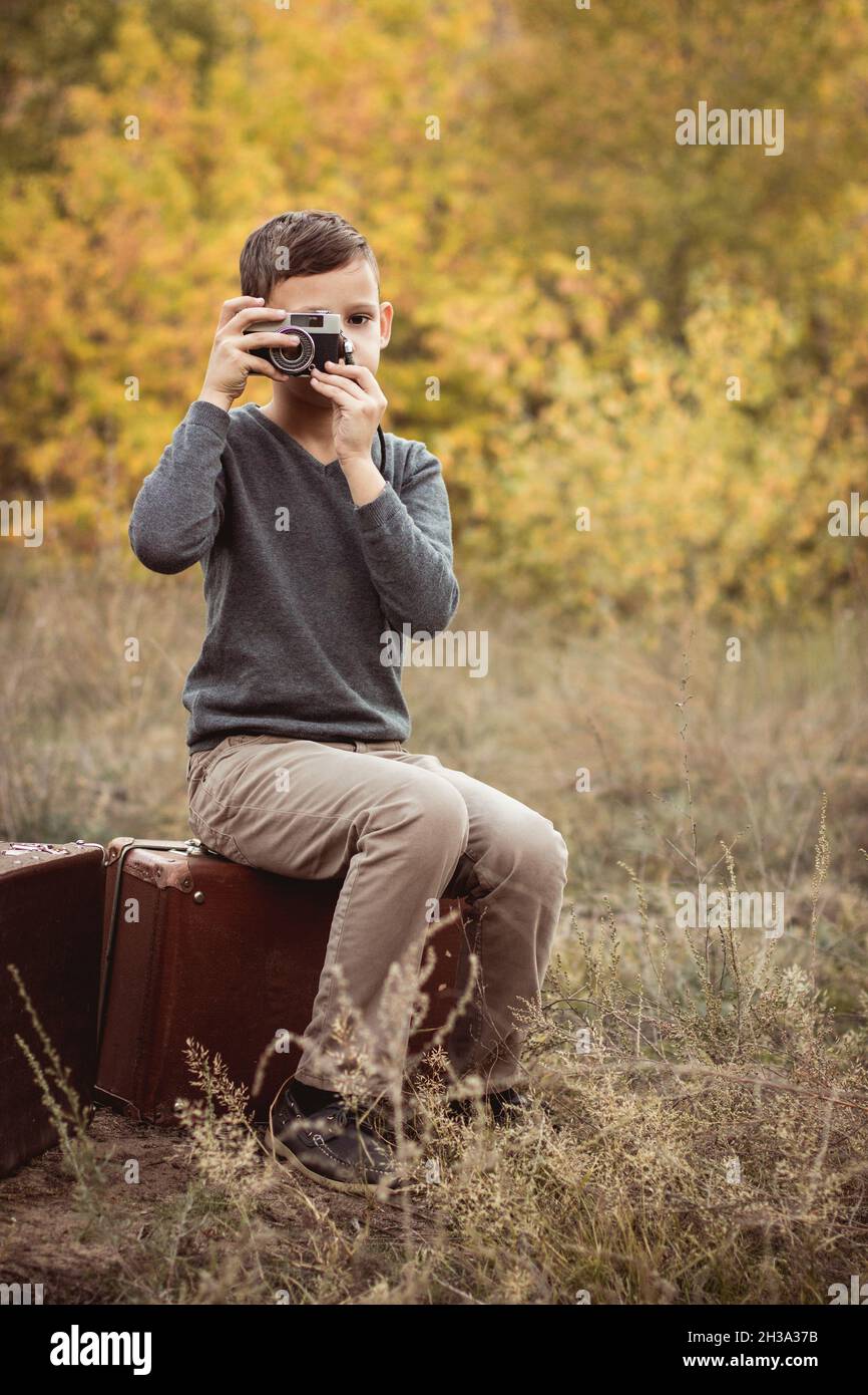 Boy holding camera. Boy taking pictures. A boy looking into camera lens