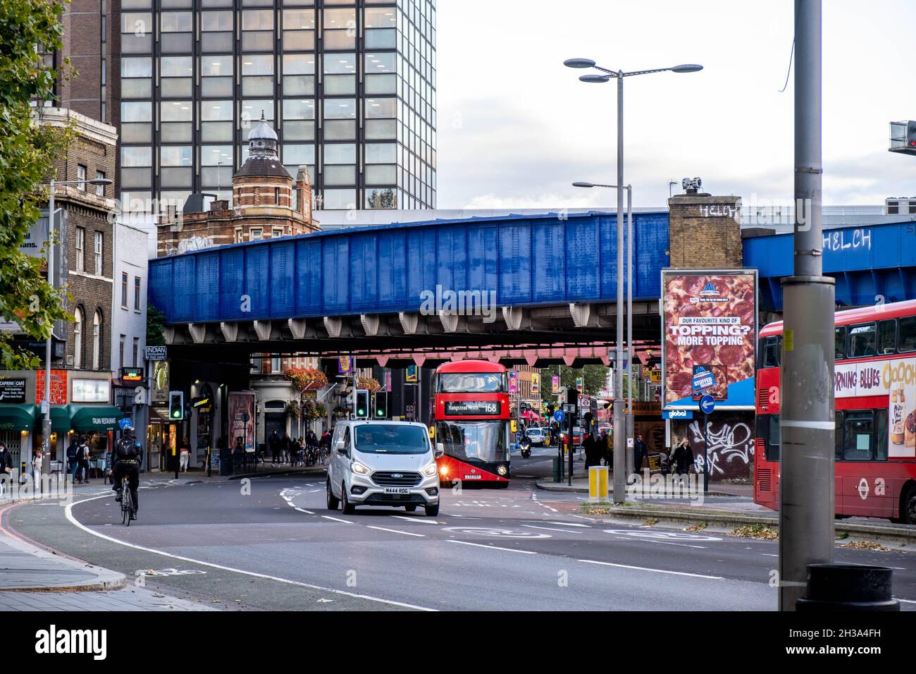 Blue Painted Railway Bridge Crossing A Busy London Street In Waterloo Central London With Traffic And Public Transport Busses And A Single Cyclist Stock Photo