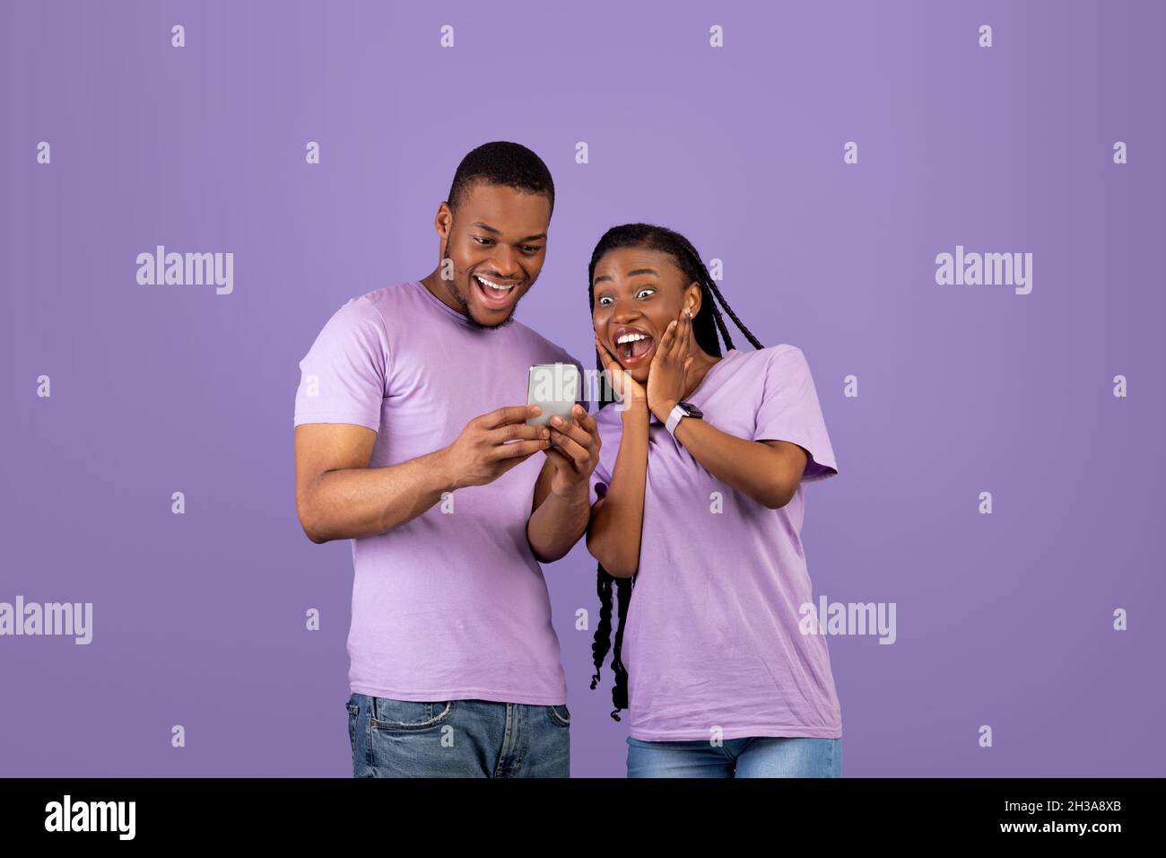 Portrait of surprised black couple using smartphone Stock Photo