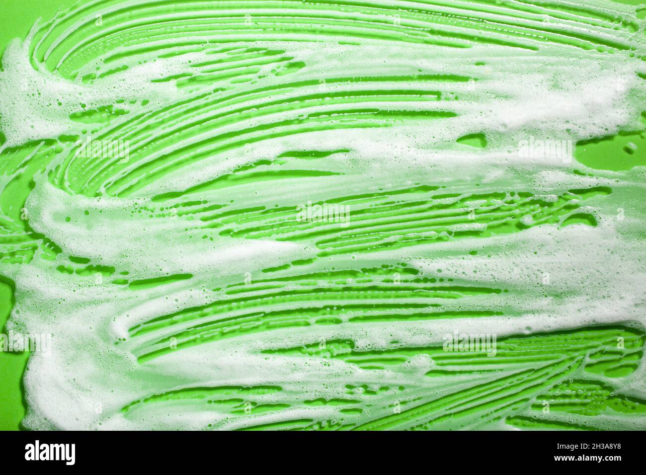 foam soap suds on green background, laundry cleaning washing concept