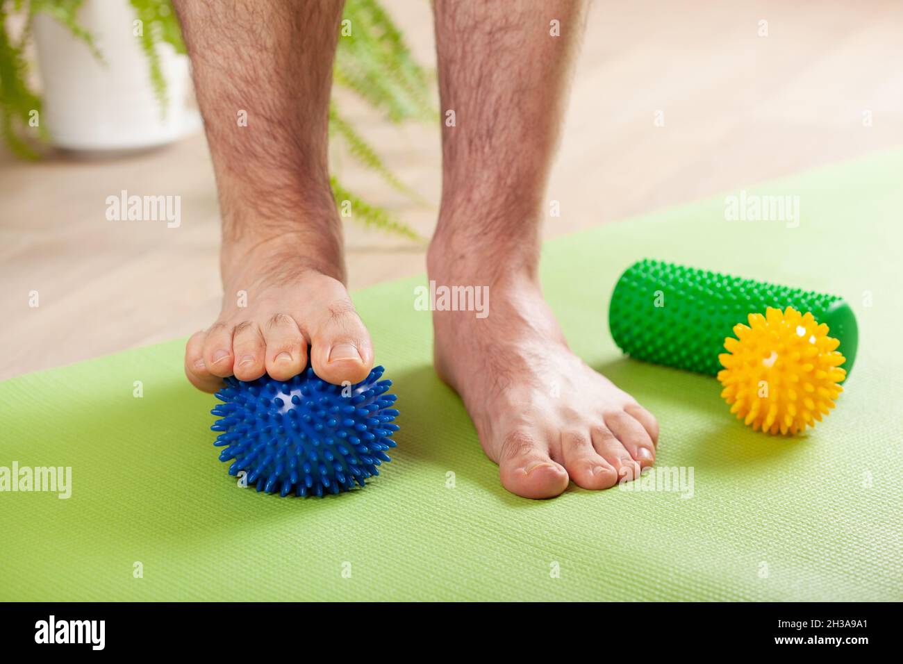 man doing flatfoot correction gymnastic exercise using massage ball at home Stock Photo