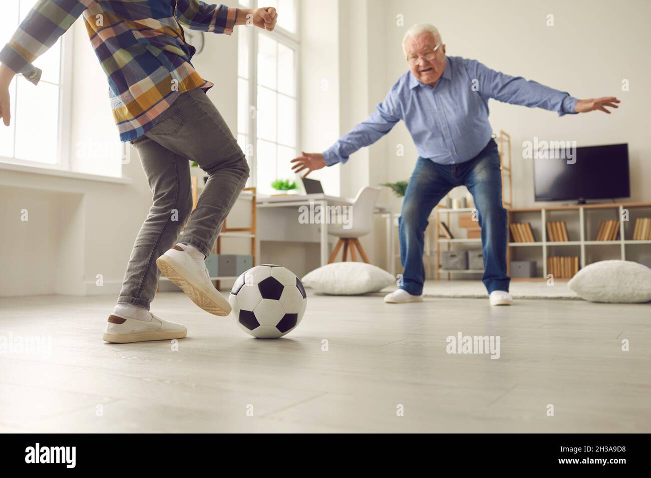 Little kid and his grandpa playing soccer at home and having fun together together Stock Photo