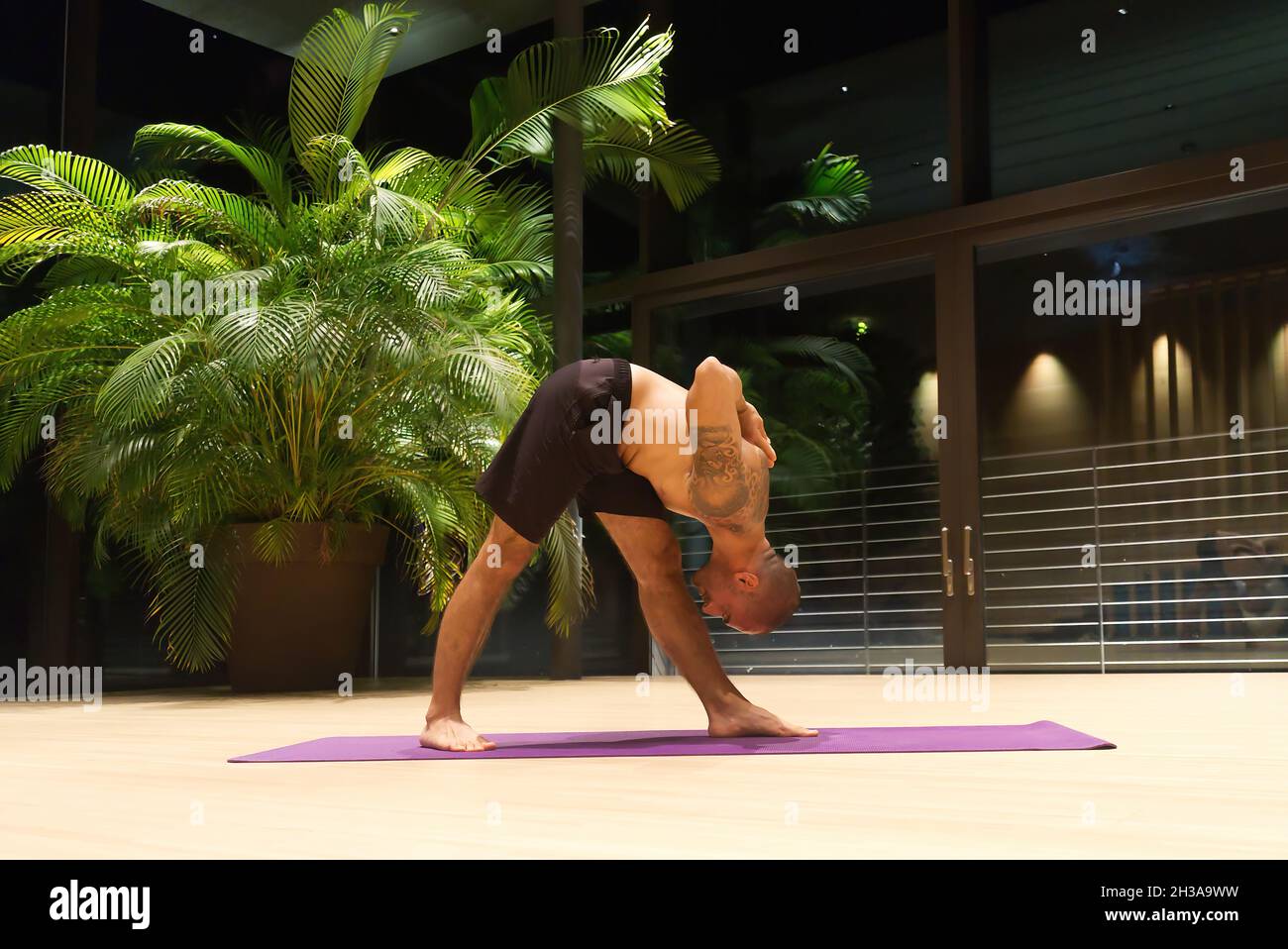 Middle aged handsome Caucasian male performs a yoga position indoors. Stock Photo