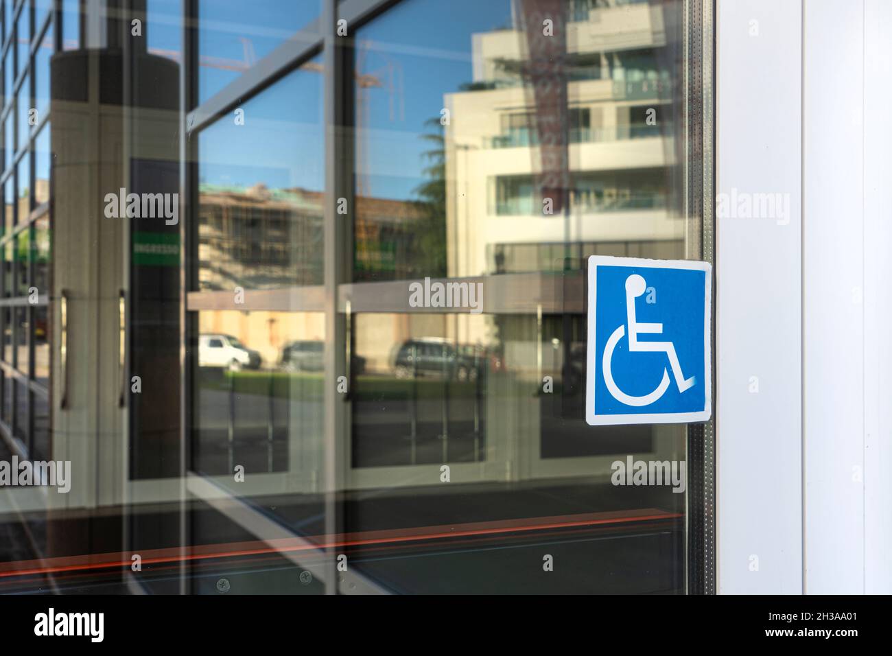 the sticker indicating the entrance for the disabled on the glass of a door Stock Photo