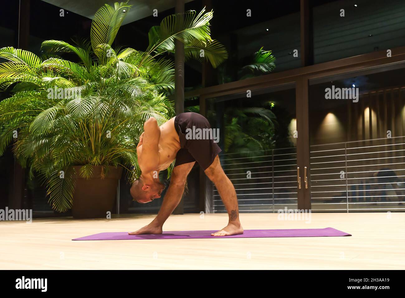 Middle aged handsome Caucasian male performs a yoga position indoors. Stock Photo