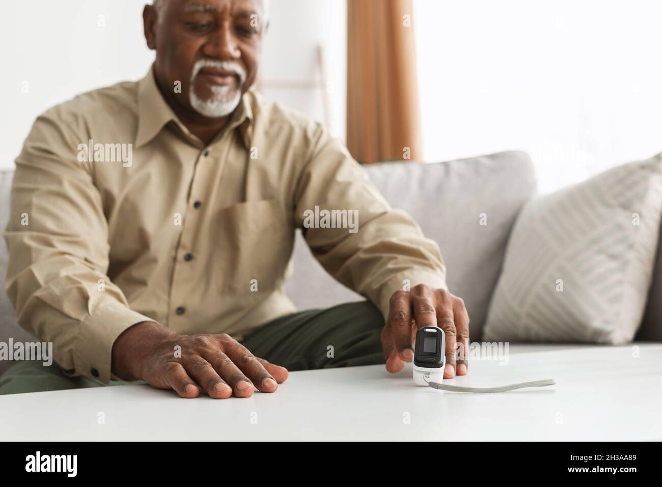 Ill Older Man With Pulse-Oxymeter Measuring Oxygen Saturation At Home Stock Photo