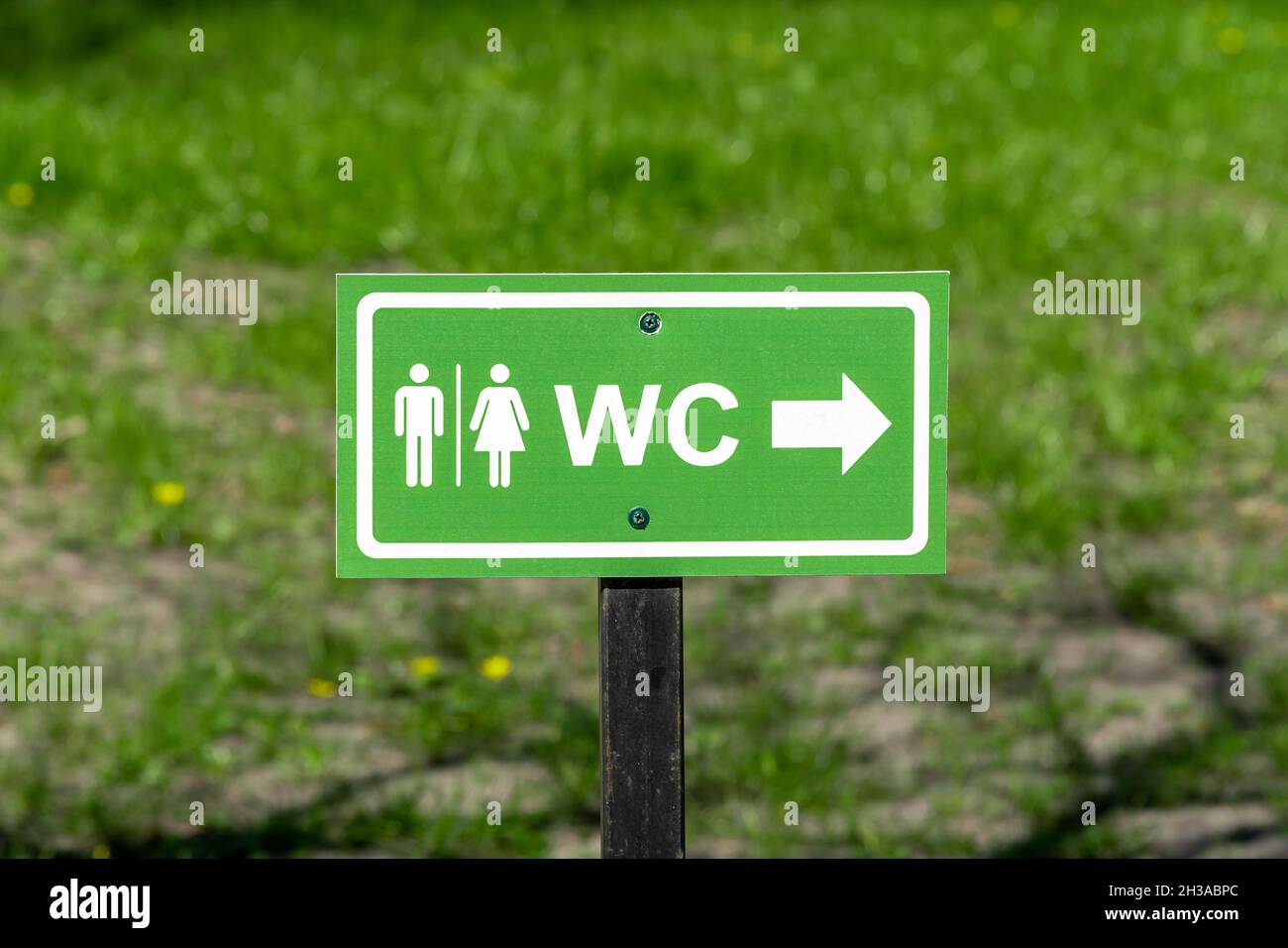 WC logo, sign of public toilets on the street against grass background. Stock Photo