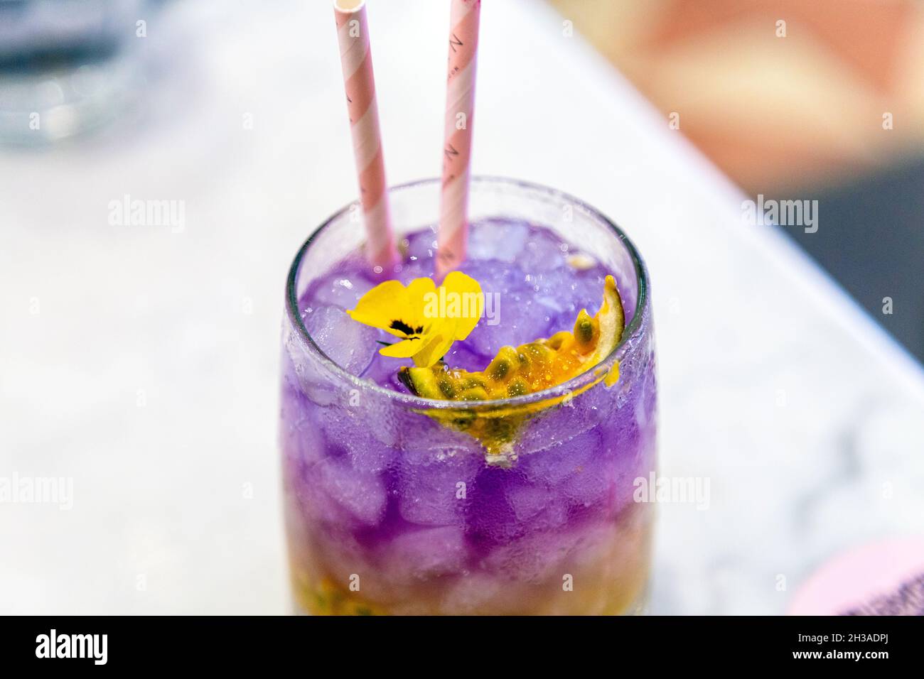 Ombre Passion Fruit Cooler with butterfly pea tea, topped with edible flowers at EL&N Cafe Brompton Road, London, UK Stock Photo
