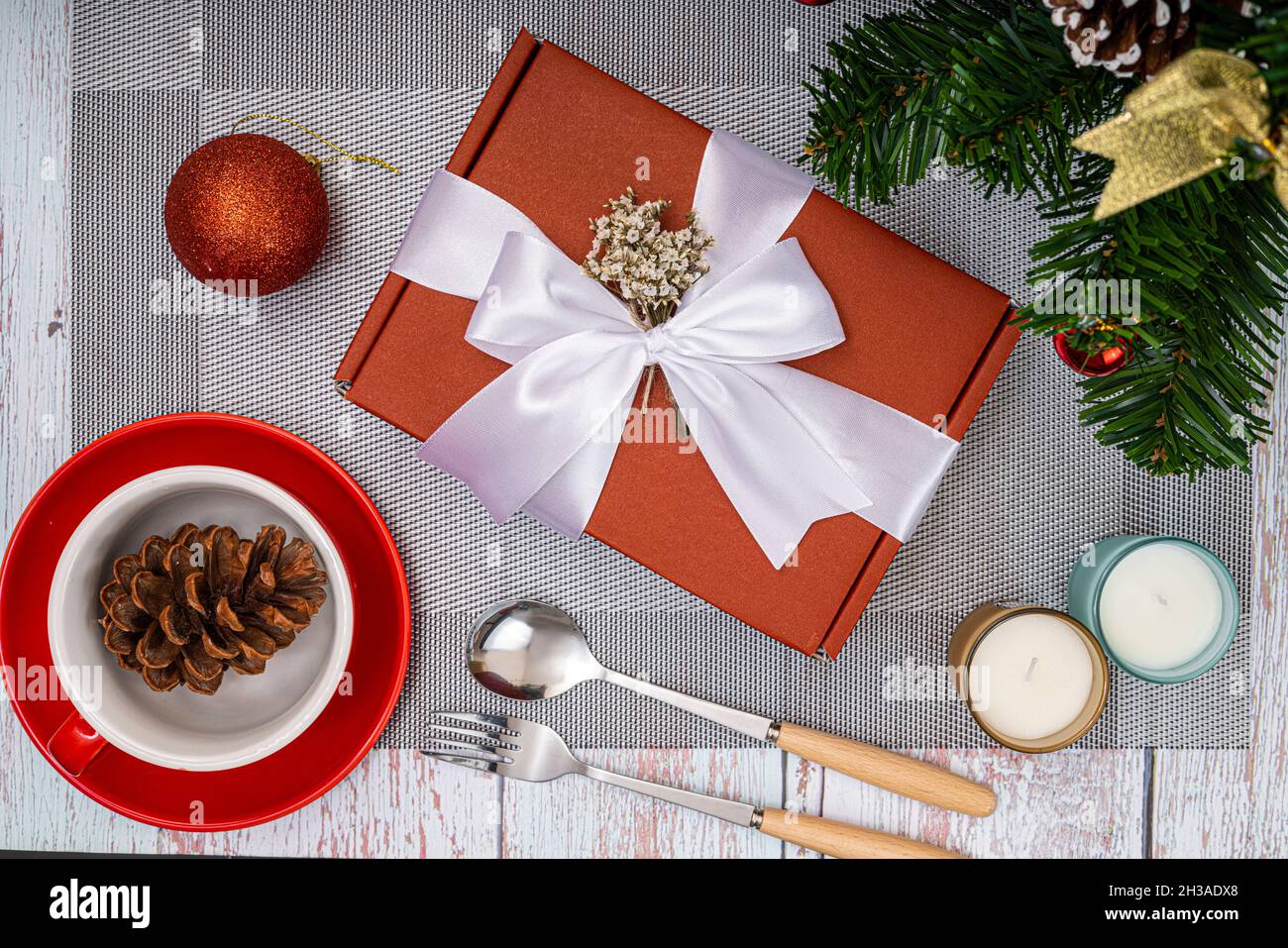 Christmas dinner table decorations with a red gift box and scented candles Stock Photo
