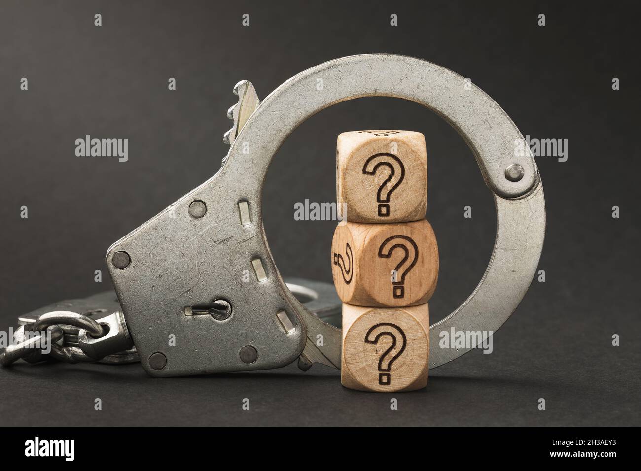 Handcuffs and wooden cubes with a question mark, guilt determination concept Stock Photo