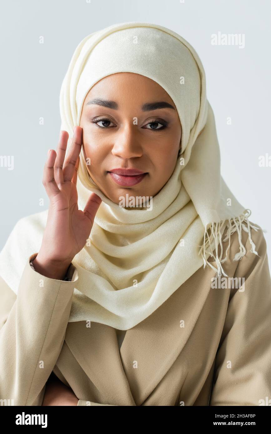 pretty muslim woman in white hijab looking at camera isolated on grey ...