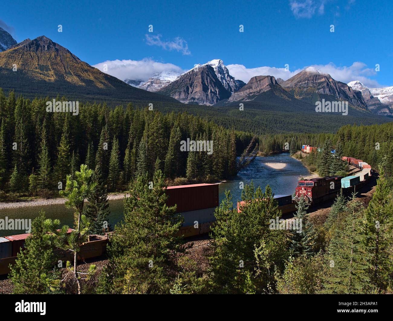Beautiful landscape in the Canadian Rocky Mountains viewed from popular Morants Curve with train moving past on sunny day in fall season. Stock Photo