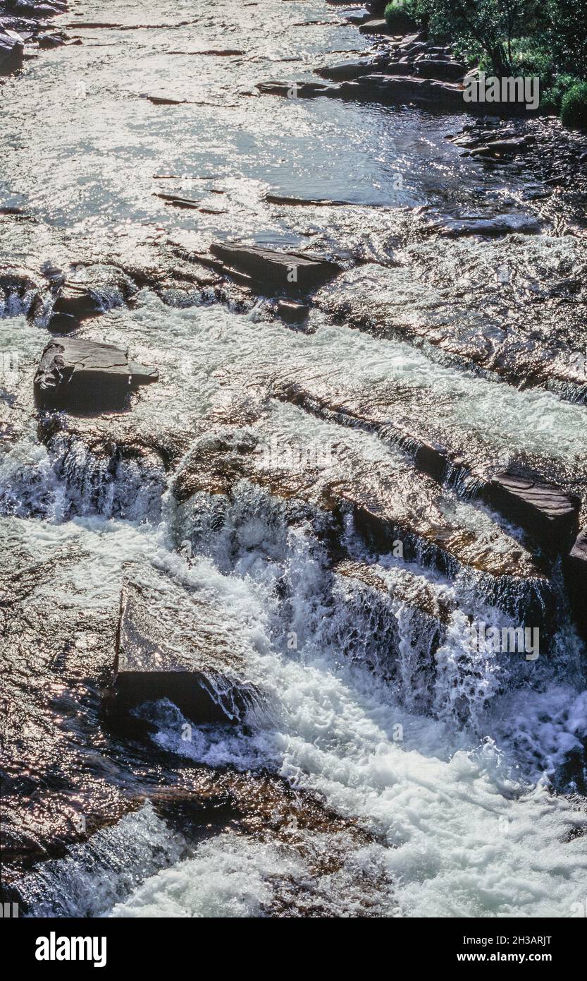stream splashing and flowing over rocks on a bright sunny day Stock Photo