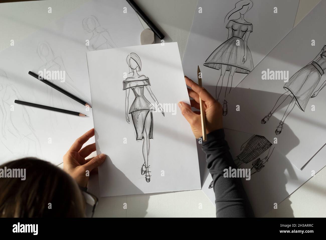 The designer draws sketches of women's dresses on paper Stock Photo - Alamy