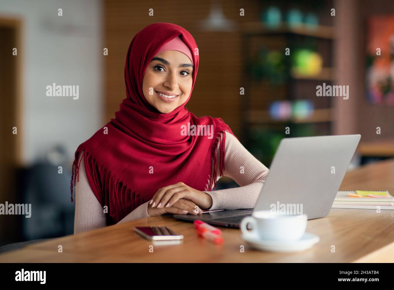 Cheerful muslim woman using modern laptop, cafe interior Stock Photo ...