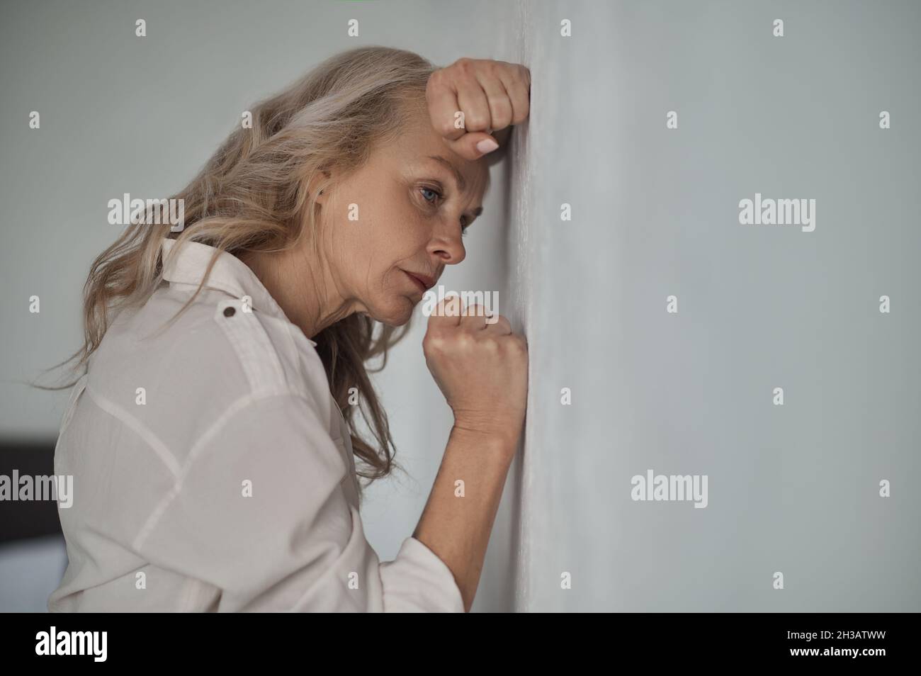 Dejected mature blonde woman suffering from loneliness Stock Photo