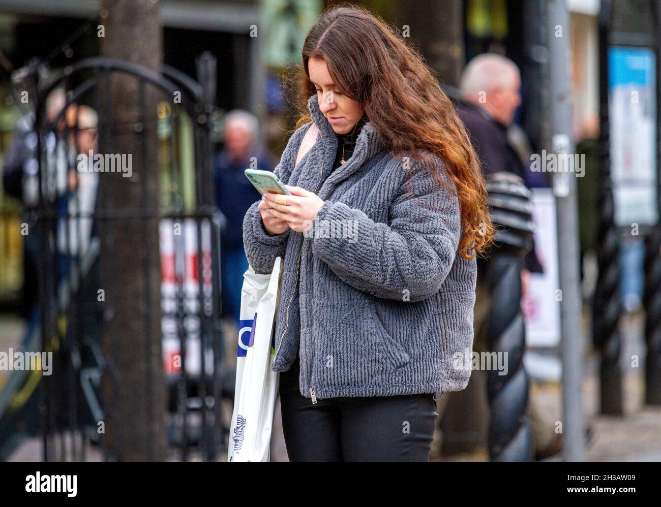 Dundee, Tayside, Scotland, UK. 27th Oct, 2021. UK Weather: A mild Autumn day with some sunny spells across North East Scotland, temperatures reaching 15°C. An attractive woman is spending the day out enjoying the October weather whilst texting messages on her mobile phone in Dundee city centre. Credit: Dundee Photographics/Alamy Live News Stock Photo