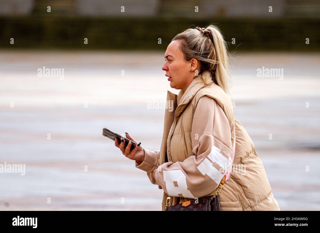 Dundee, Tayside, Scotland, UK. 27th Oct, 2021. UK Weather: A mild Autumn day with some sunny spells across North East Scotland, temperatures reaching 15°C. An attractive woman is spending the day out enjoying the October weather whilst texting messages on her mobile phone in Dundee city centre. Credit: Dundee Photographics/Alamy Live News Stock Photo