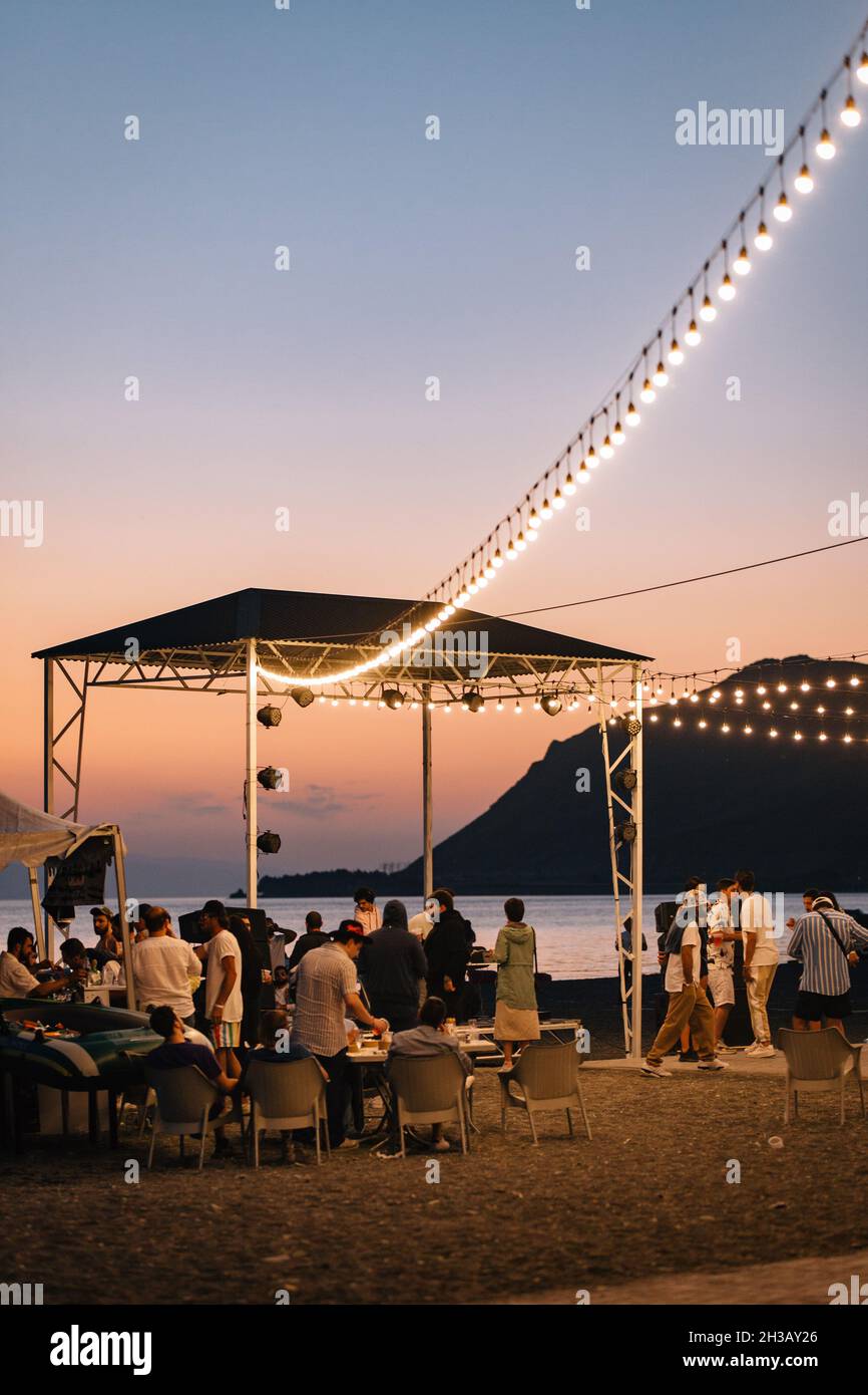 SEVAN, ARMENIA - Sep 03, 2021: A group of young people enjoying the beach party on the shore of Lake Sevan at sunset Stock Photo