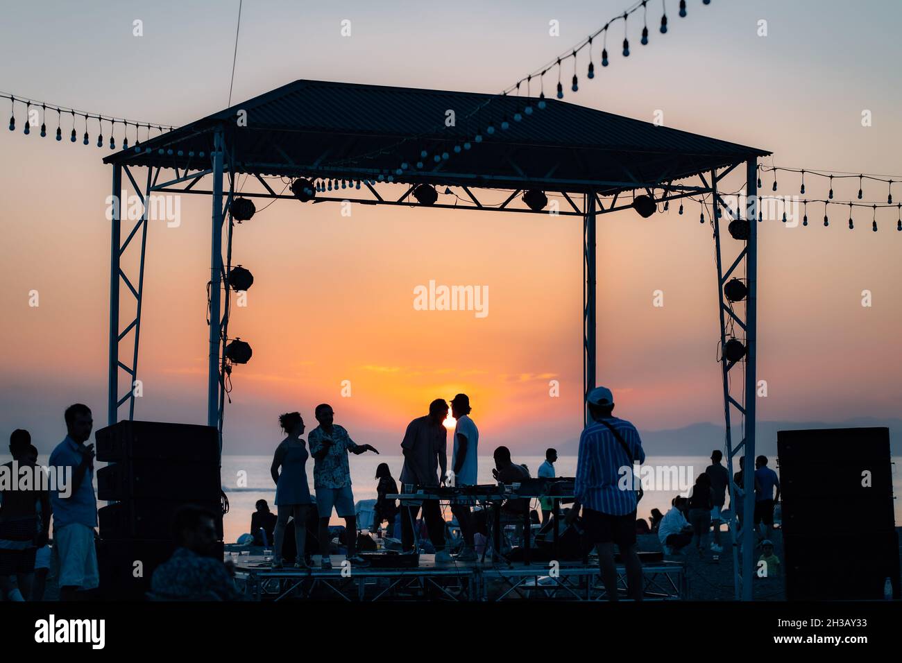 SEVAN, ARMENIA - Sep 03, 2021: A group of young people enjoying the beach party on the shore of Lake Sevan at sunset Stock Photo