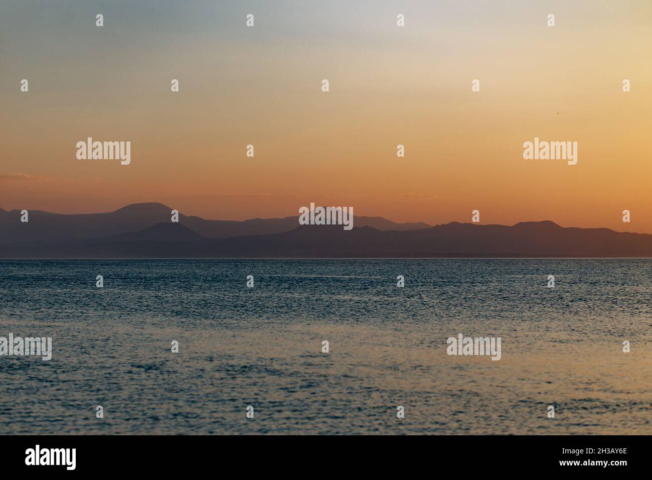Stunning view of Lake Sevan with the silhouette of mountain range layers in the background at sunset Stock Photo