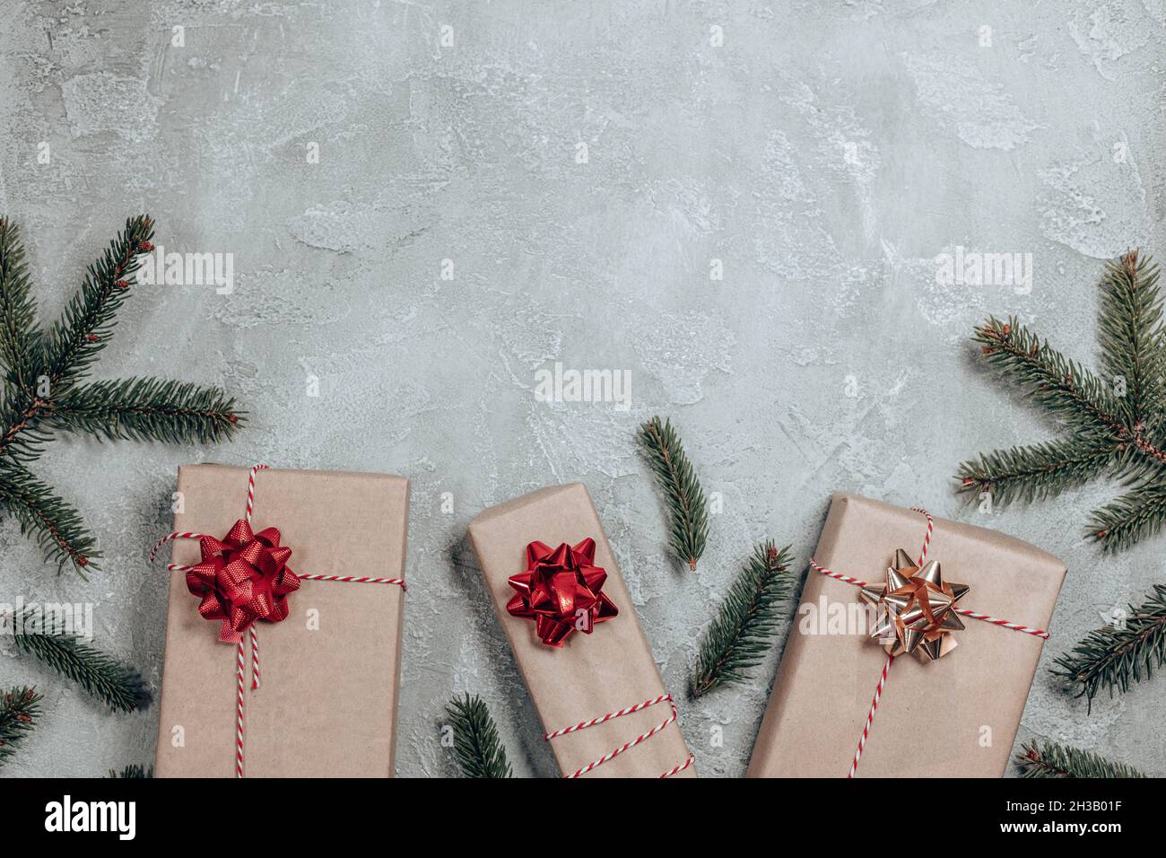 Fir tree branch and gift box, paper decorations on grey background. New Year holiday background. Flat lay, top view Stock Photo