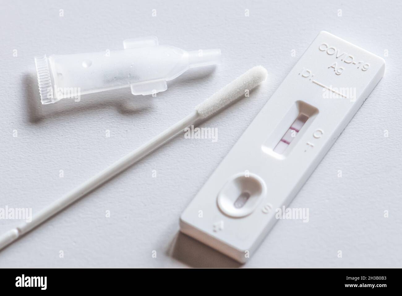 Positive Covid-19 antigen test kit, one step coronavirus antigen rapid test, saliva swab, on a white table, close up Stock Photo