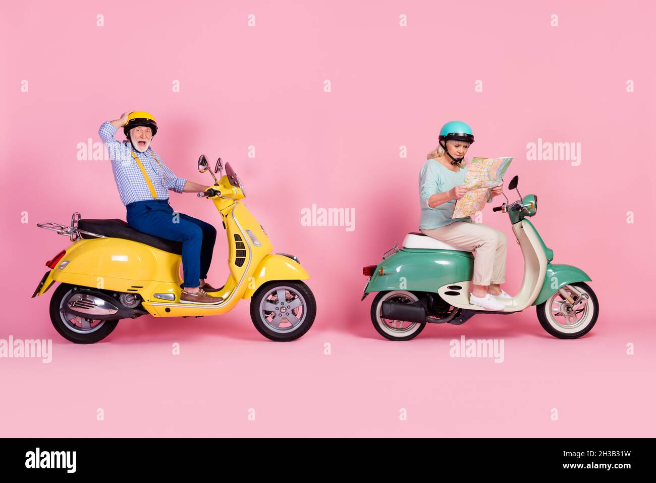 Full body profile side photo of aged friend ride scooter lost look map vacation tourism isolated over pink color background Stock Photo