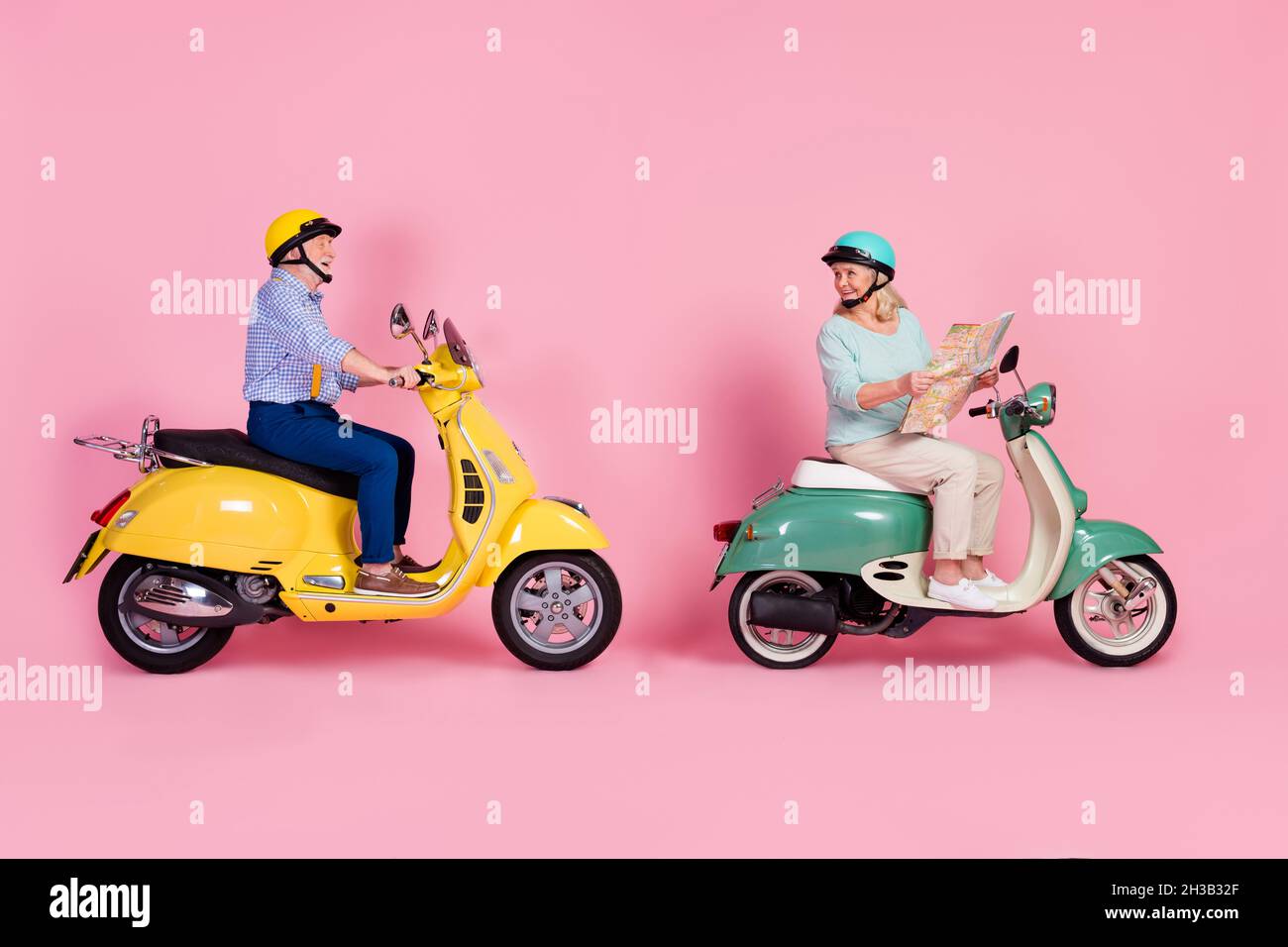 Full size profile side photo of smiling mature couple white grey hair ride moped hold map checking route isolated on pink color background Stock Photo