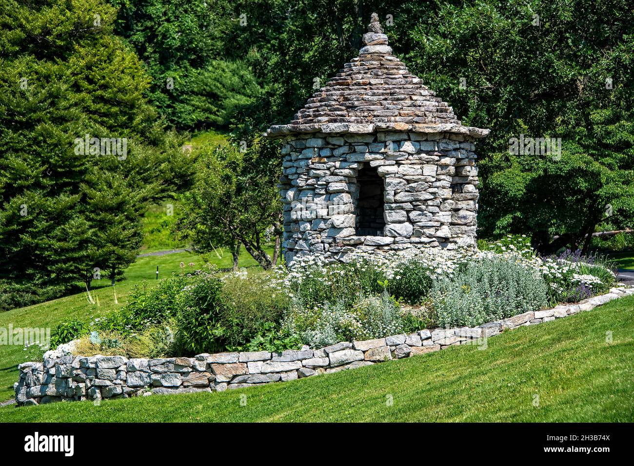 Small stone structured gazebo with flower garden and stone wall, on the grounds at Mohonk Mountain House in upstate New York. Stock Photo