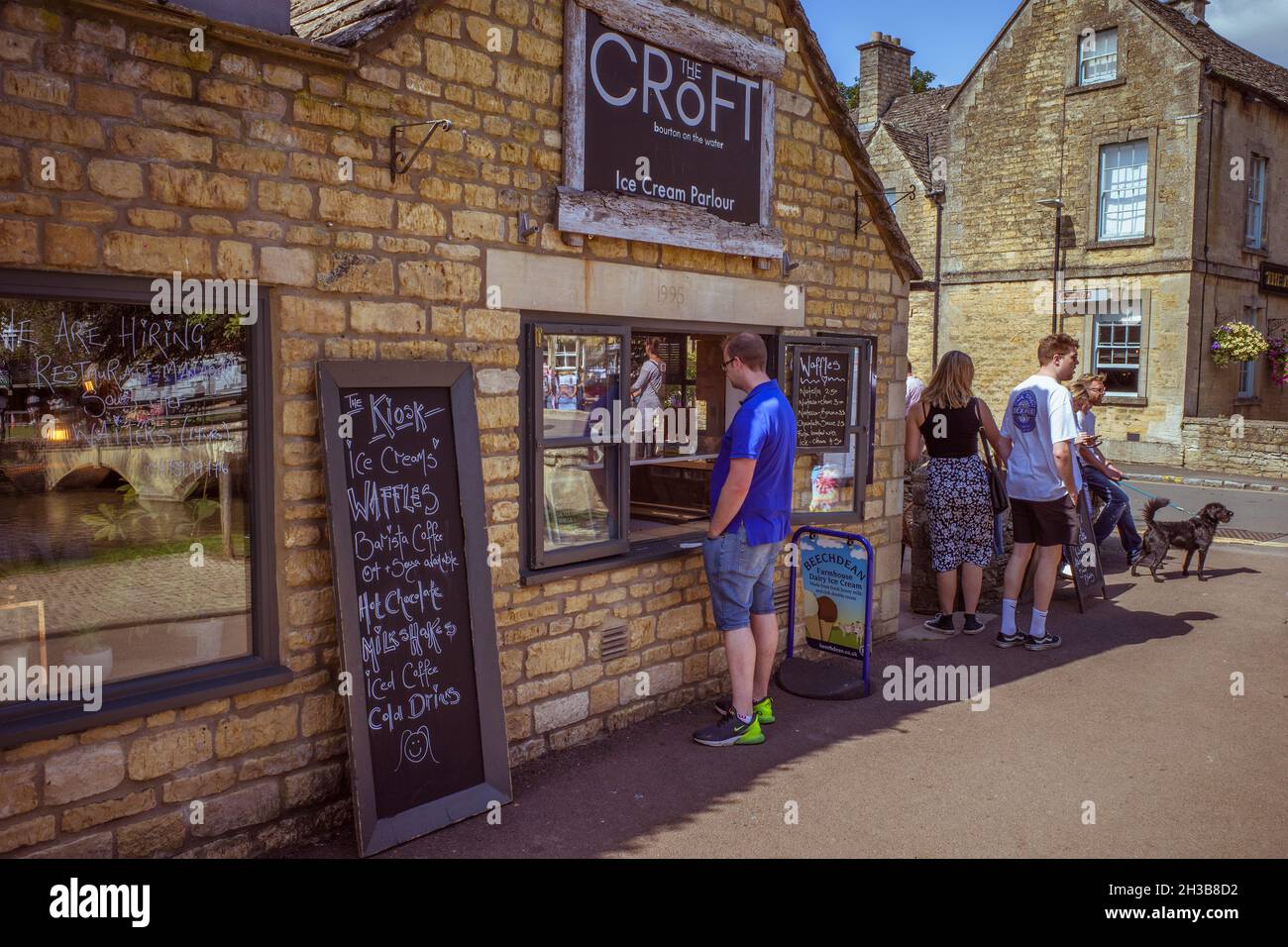A customer buying refreshments at an ice cream parlour on a hot summer's day in Bourton On The Water. A picturesque village in the Cotswolds, UK. Stock Photo