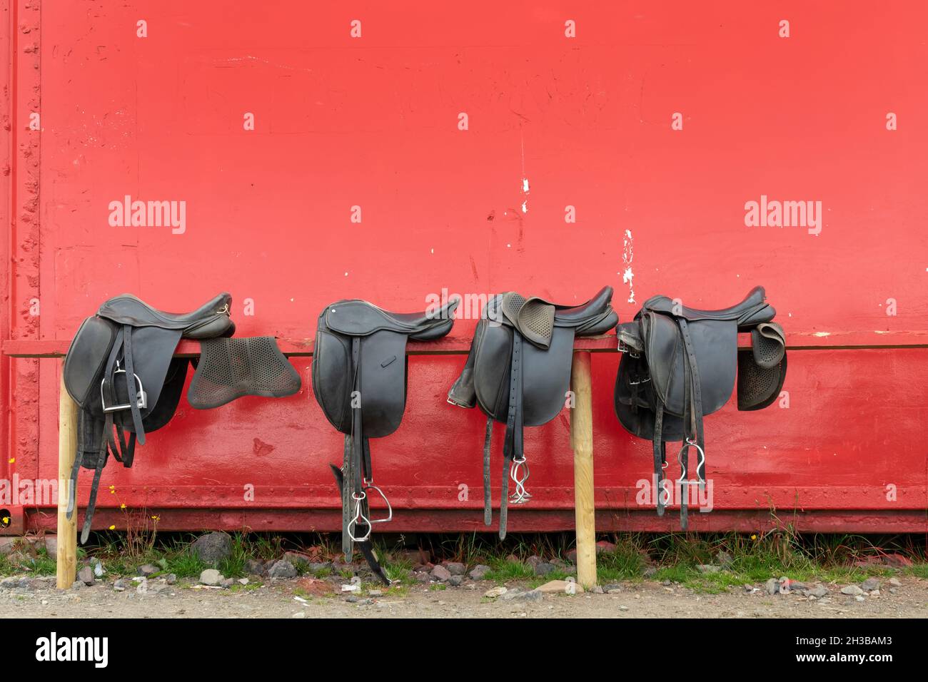 Brown leather horse saddles before the ride on red background Stock Photo