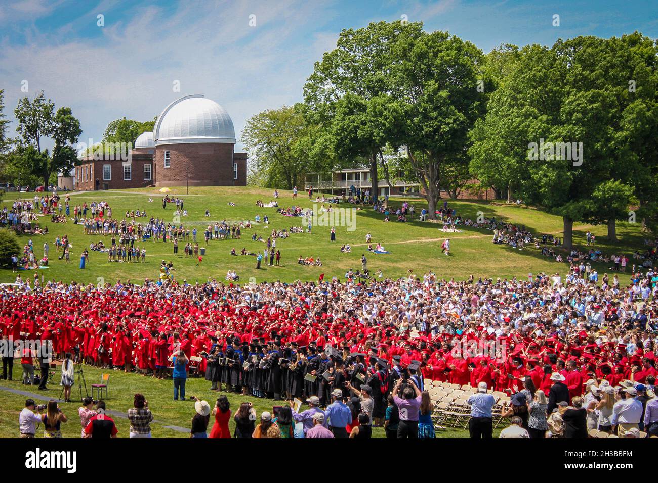 04-25-2015 Middletown CT USA Looking down on graduates and crowd sitting in seats and on the ground for graduation ceremony with observatory in the ba Stock Photo