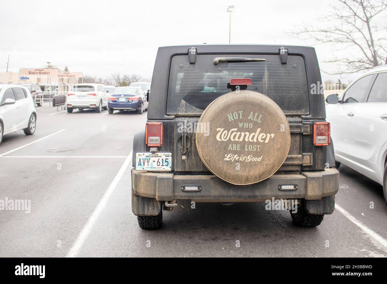 2019 01 12 Tulsa OK USA Dark dirty off road jeep parked in parking lot with wheel cover reading All Who Wander are Not Lost - Life is Good Stock Photo