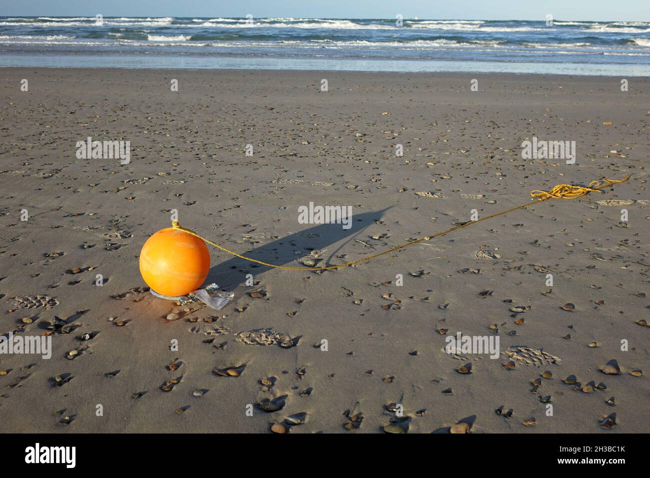 Shiny orange plastic float with yellow rope washed ashore at Skagen ...