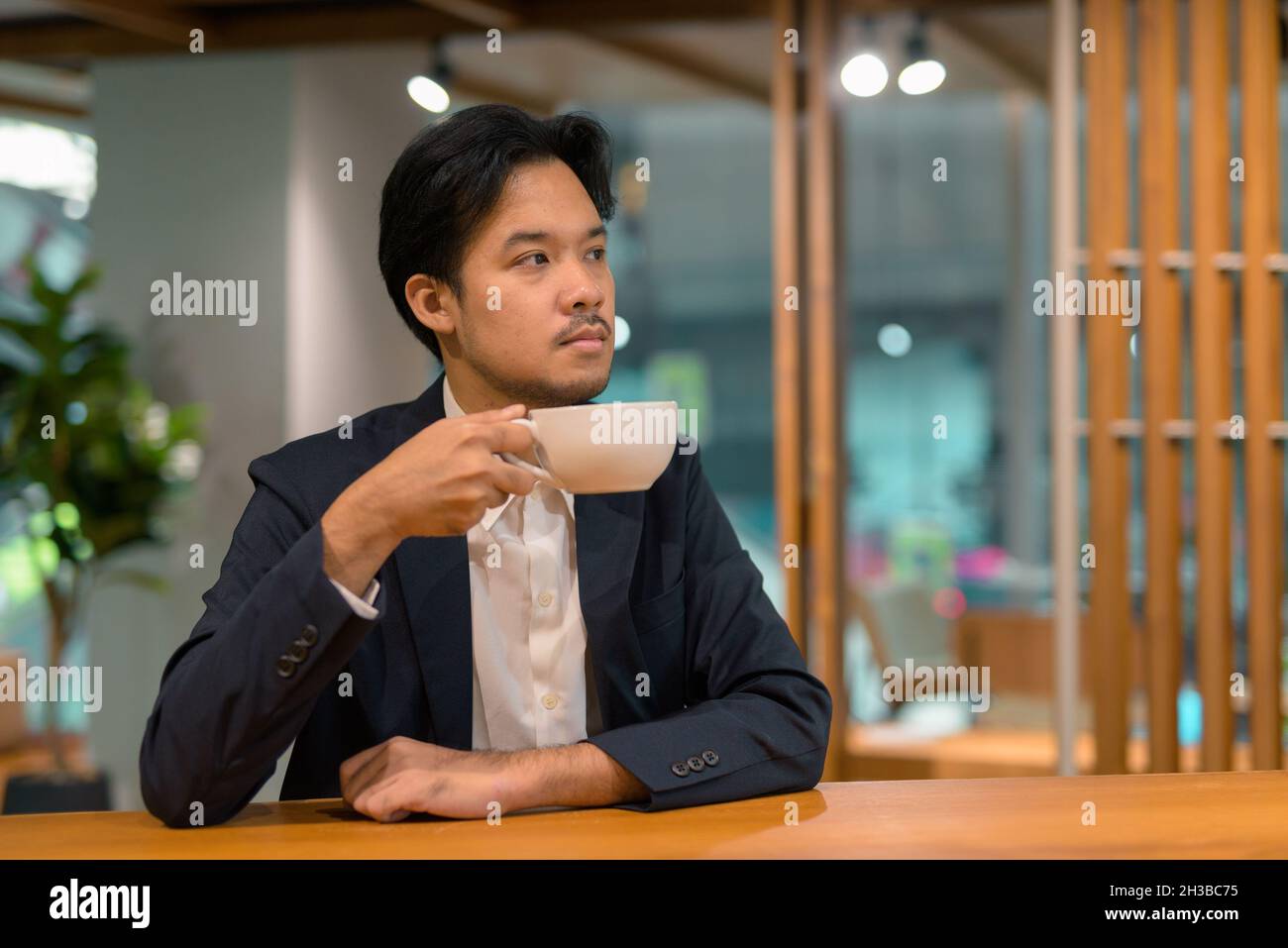 Portrait of Asian businessman sitting at restaurant and drinking coffee Stock Photo